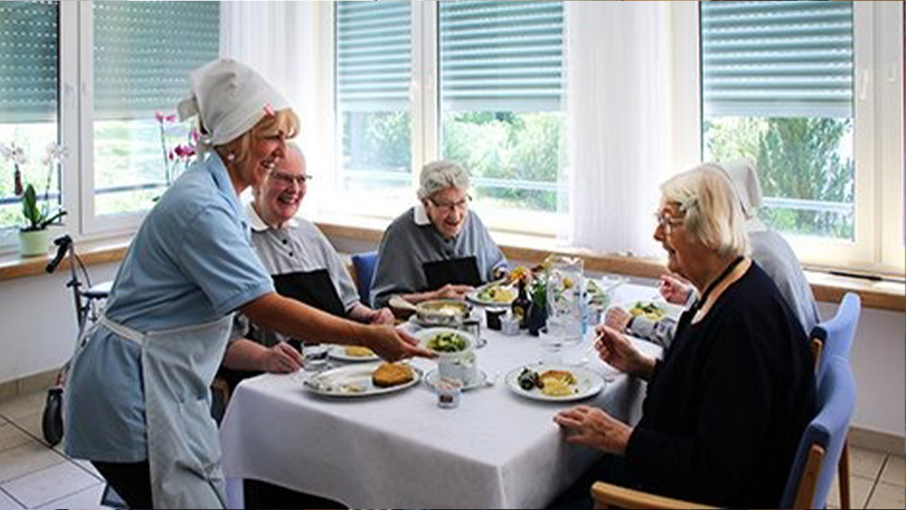 Evdiak Bild von Senioren an einem Tisch, ihnen wird Essen gereicht
