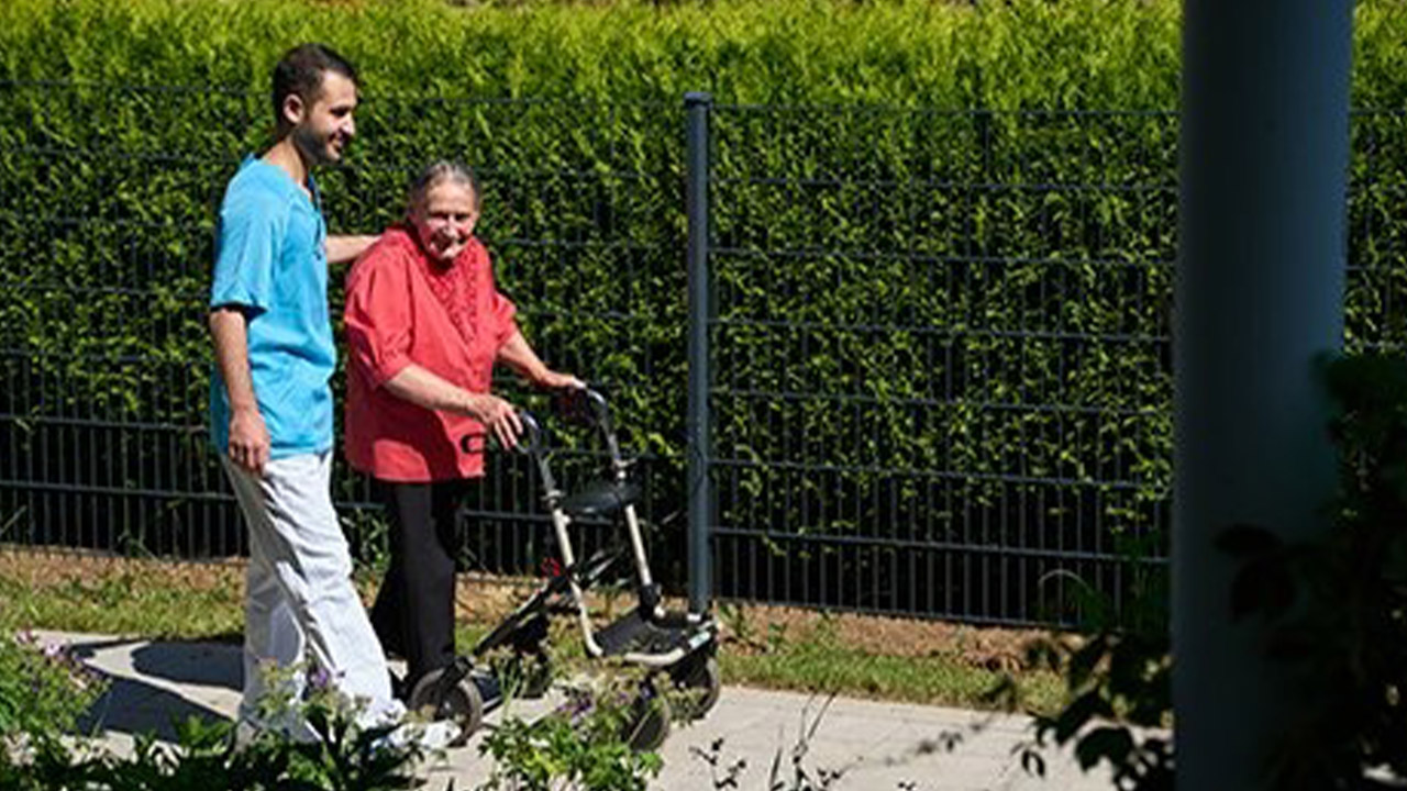 Evdiak Bild von einem Pfleger und einer Seniorin beim Spazierengehen