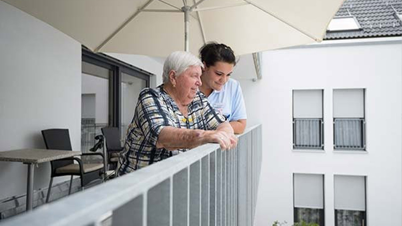 Evdiak Bild von einer Pflegerin und einer älteren Person auf einem Balkon