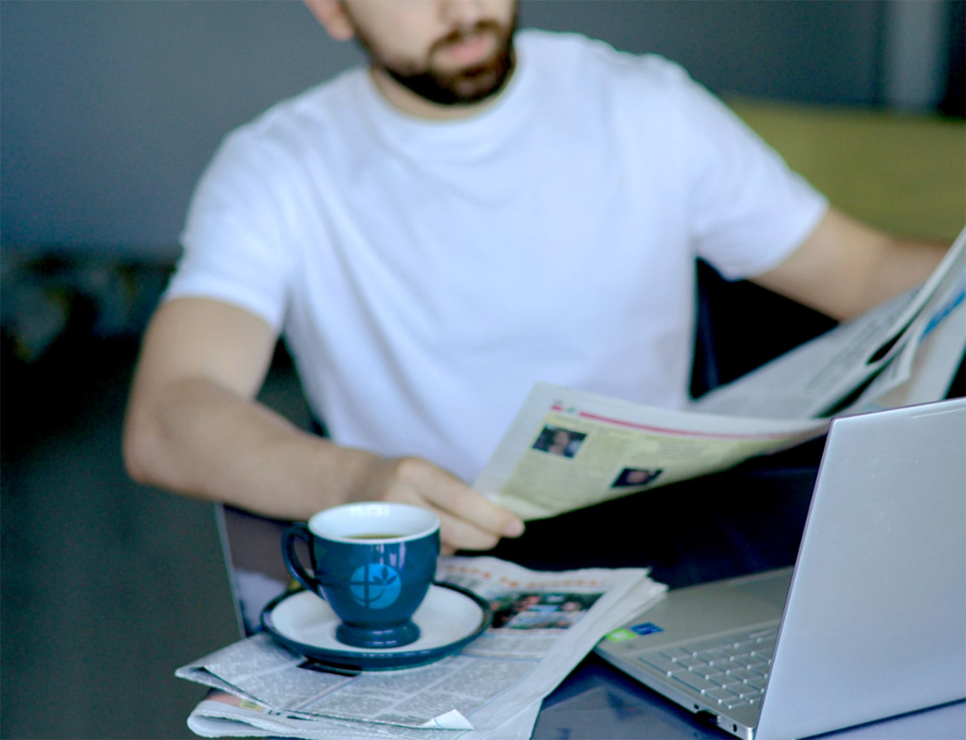 Evdiak Bild eines Mannes, der Zeitung liest. Vor ihm steht eine Tasse mit dem Evdiak Logo darauf