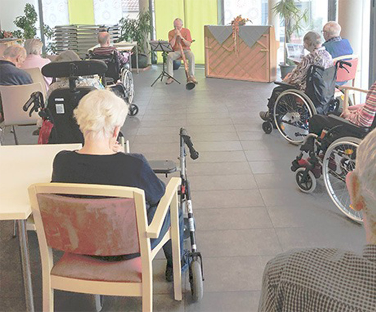 Veranstaltung von einem Mann, der Didgeridoo spielt und Senioren die zuschauen