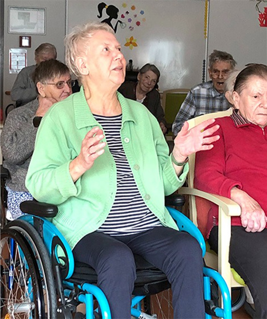 Evdiak Bild einer Seniorin im Rollstuhl, die in die Hände klatscht