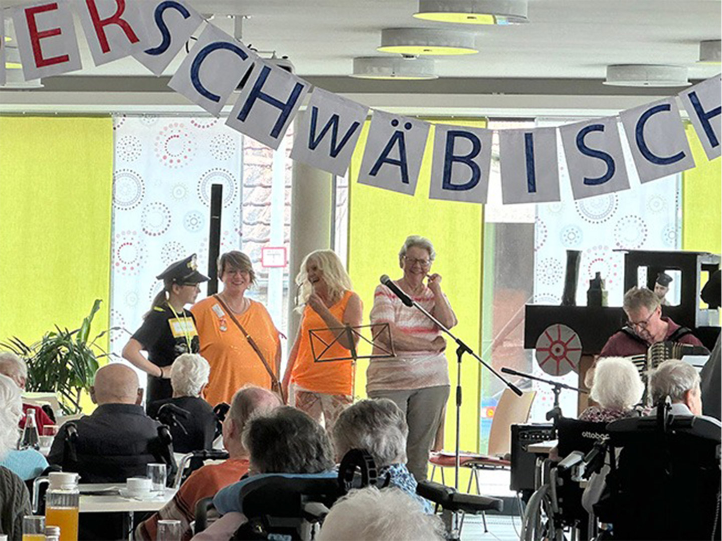 Evdiak Bild von Personen auf einer Bühne und einem Seniorenpublikum