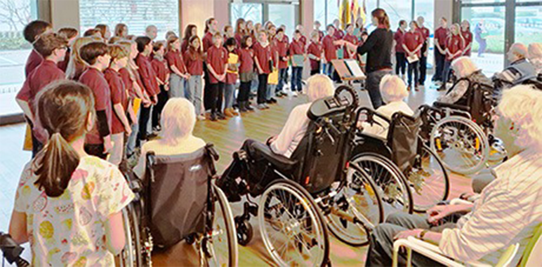 Evdiak Bild von einem Kinderchor, der singt und einem Seniorenpublikum