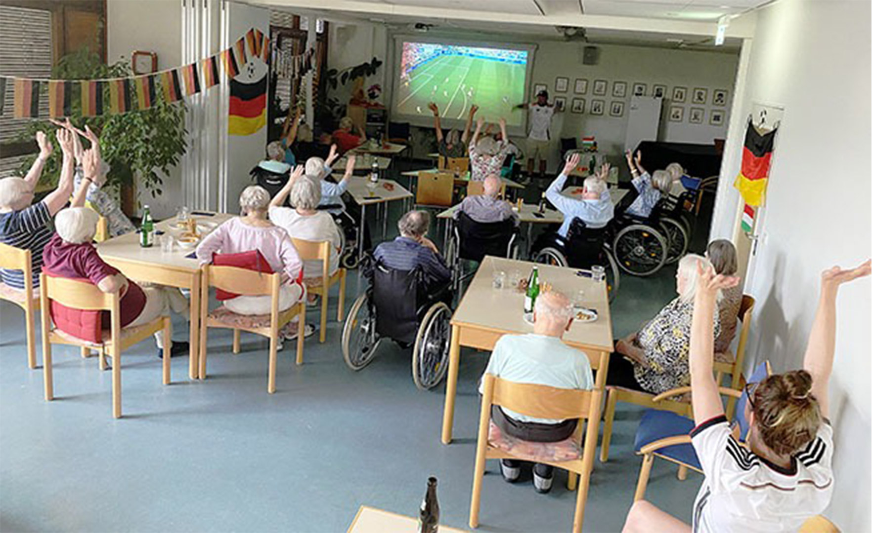 Evdiak Bild von Senioren die auf eine Leinwand mit einem Fußballspiel der EM schauen