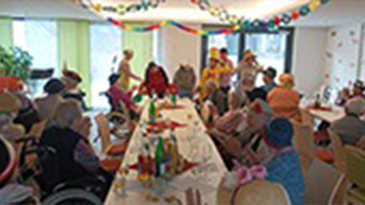 Evdiak Bild einer langen Tafel mit Senioren, alles ist bunt geschmückt