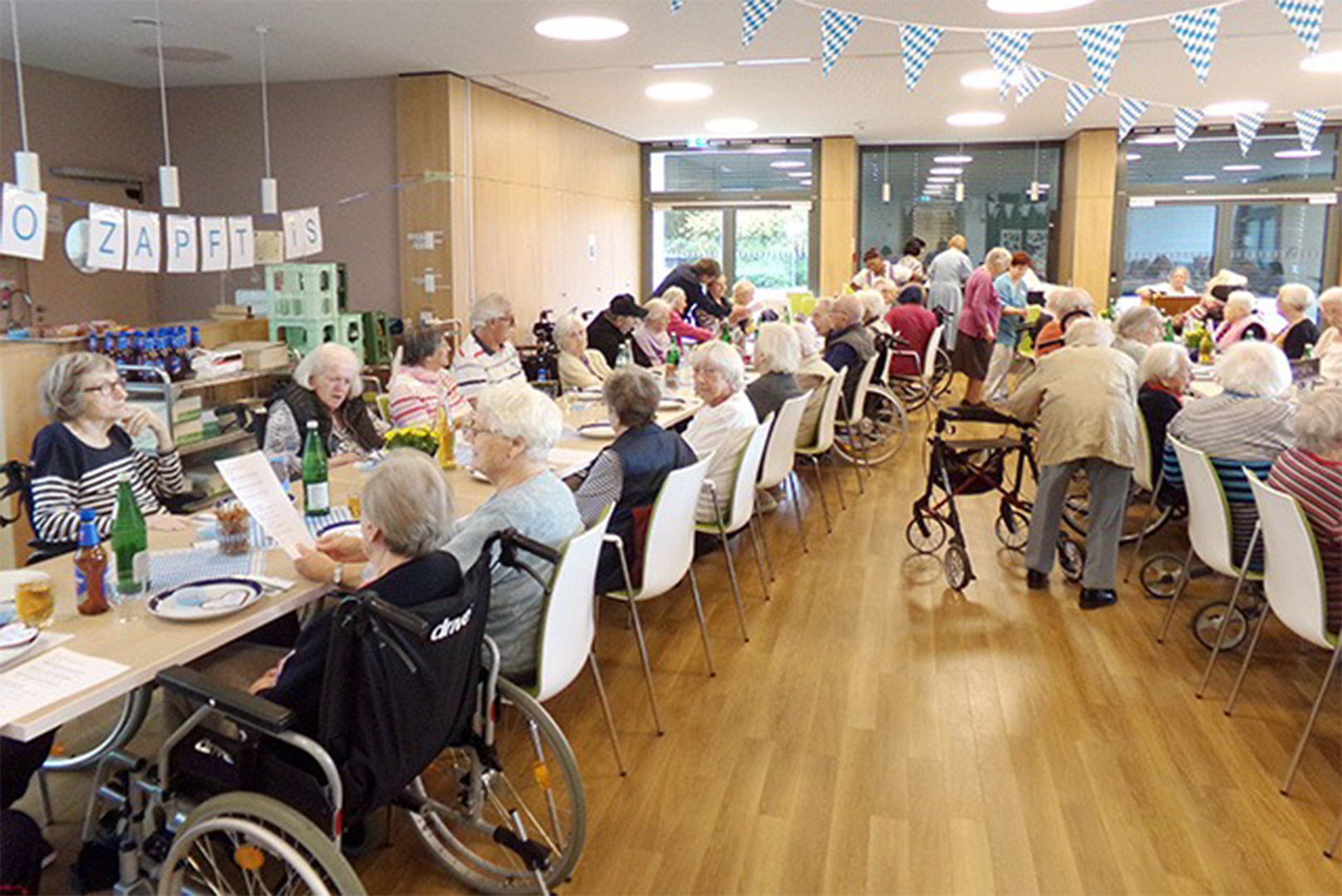 Evdiak Bild von langen Tischen, an denen Senioren sitzen. Es ist feierlich geschmückt