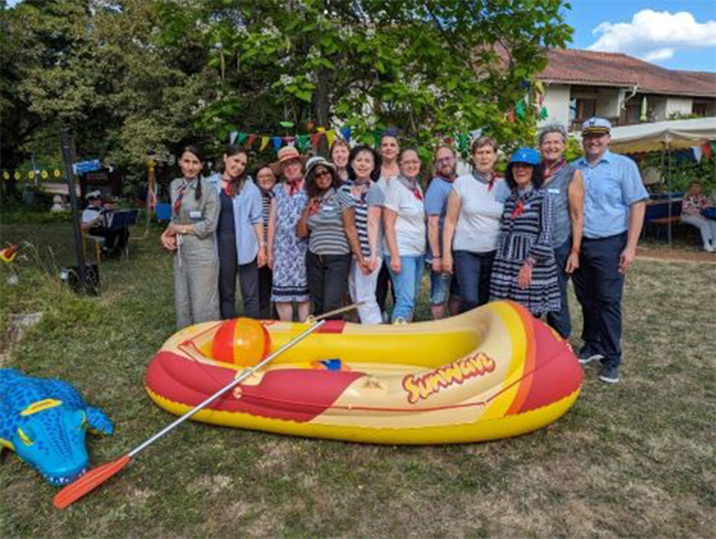 Evdiak Bild von einem Schlauchbott auf einer Wiese und einer Menschengruppe dahinter.