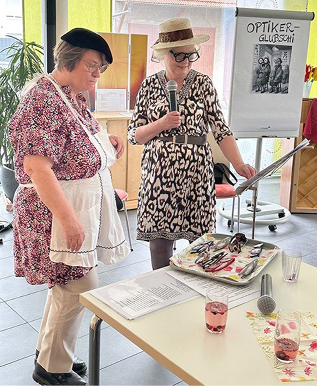 Evdiak Bild von zwei Frauen, die am Tischende stehen und ein Mikrophon halten