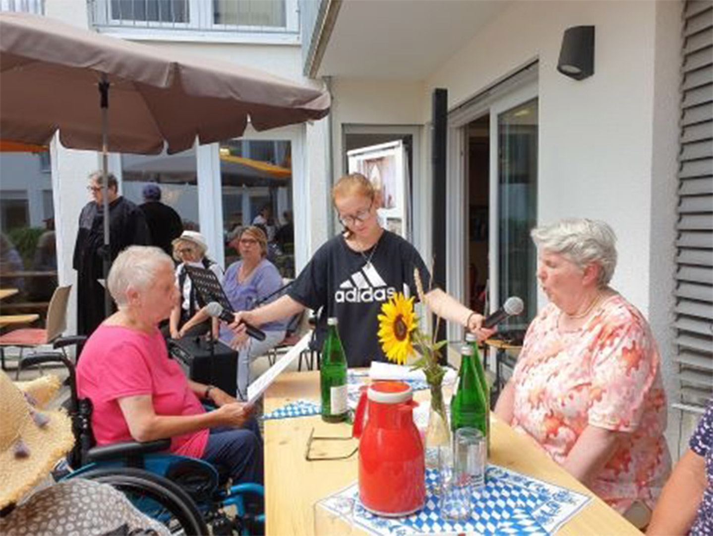 Evdiak Bild auf dem zwei am Tisch sitzende Seniorinnen in Mikrophone sprechen