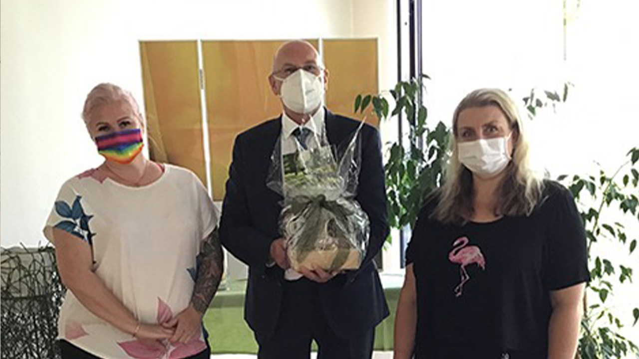 Evdiak Bild von drei Personen, in der Mitte der Pastor mit einem Abschiedsgeschenk