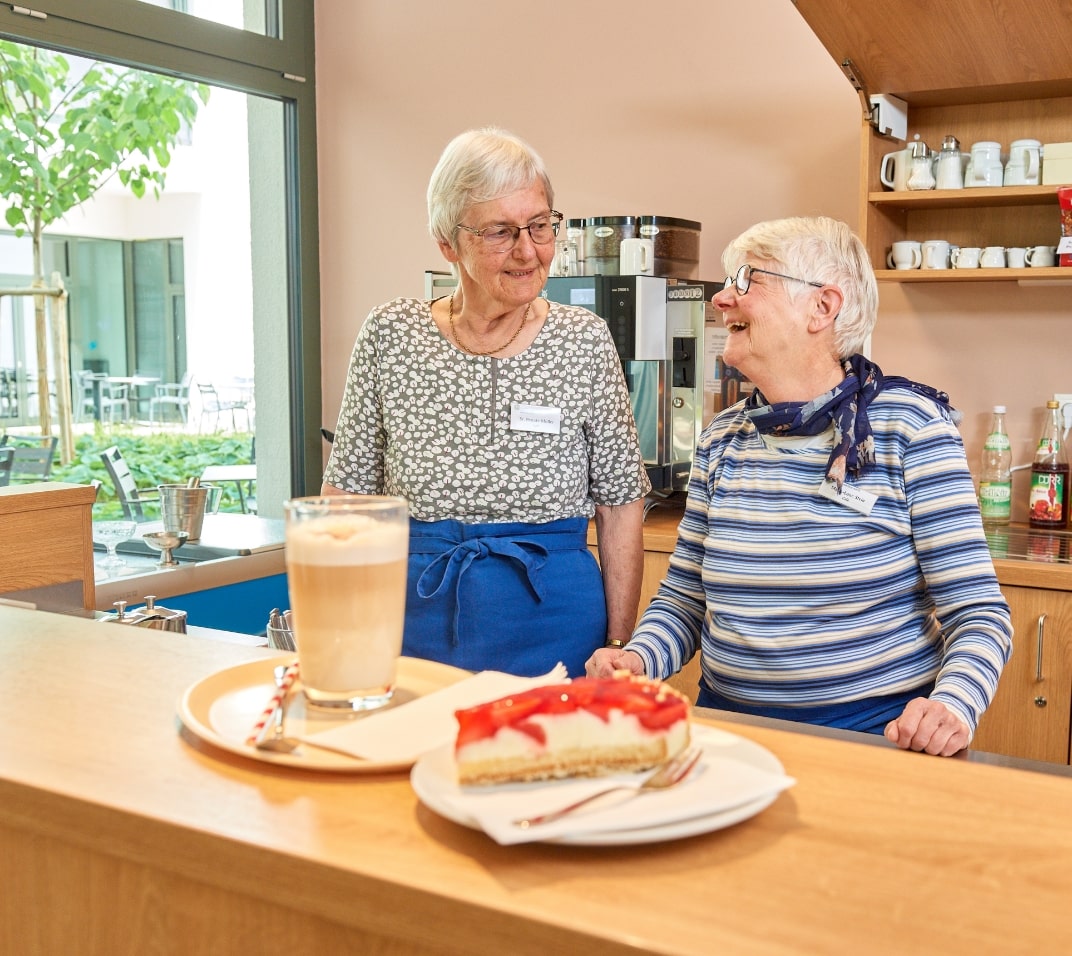 Evdiak Zwei fröhliche Seniorinnen beim Servieren von Kaffee und Erdbeerkuchen